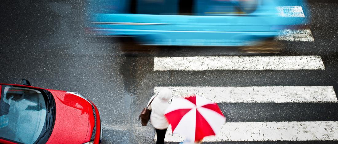 A topical view of a person in a crosswalk during rainfall