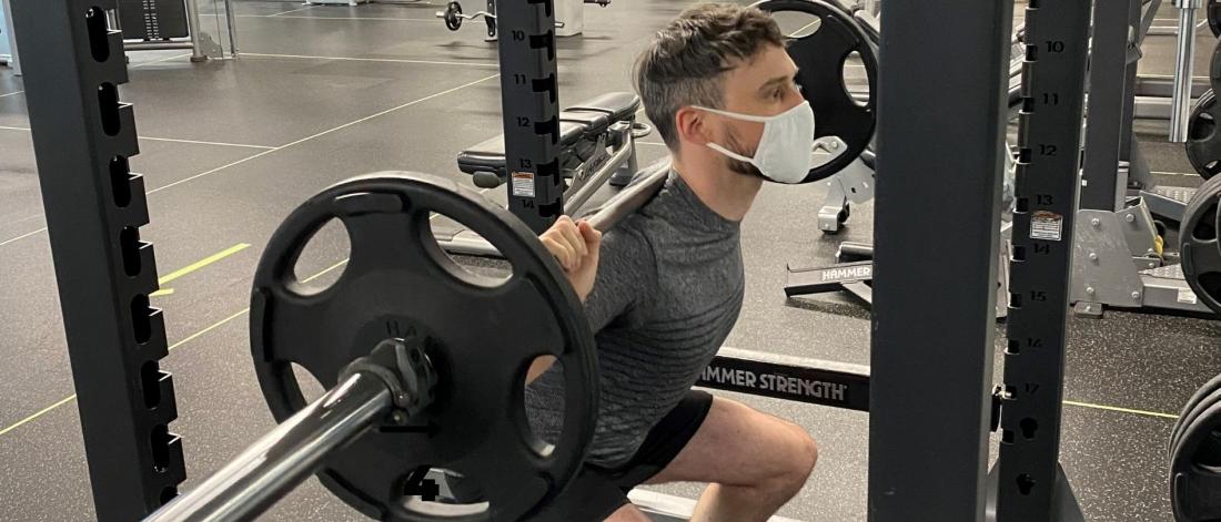 Man Lifting Weights While Wearing A Mask