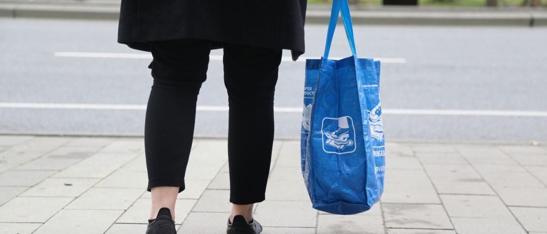 Person holding a blue re-useable shopping bag