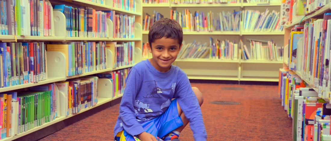 Boy sitting in a library holding a book