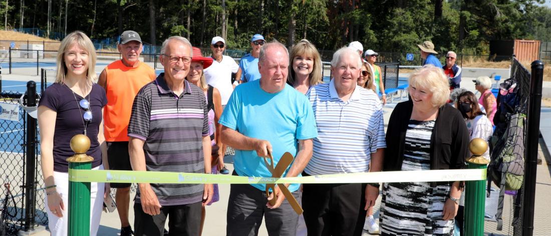 Mayor McCallum and others stand for a ribbon cutting ceremony outdoors
