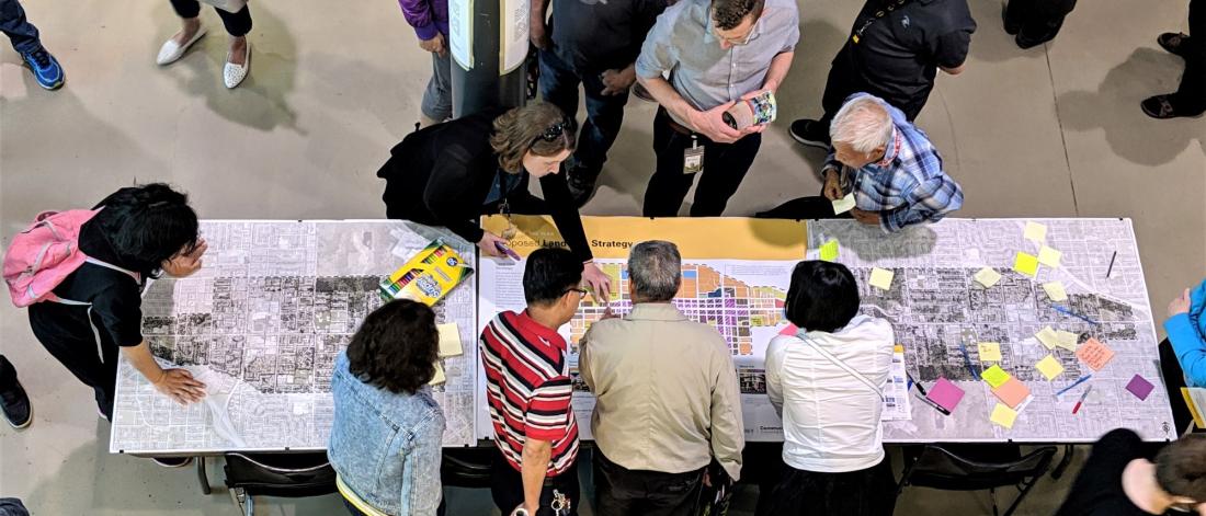 A bird's eye view of people huddled around a large map on a table