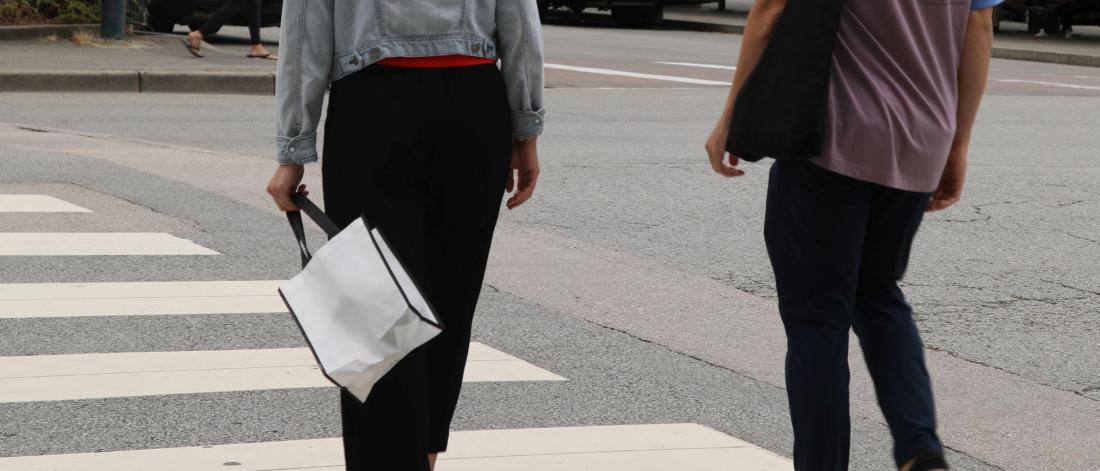 Two people in a crosswalk carrying cloth bags