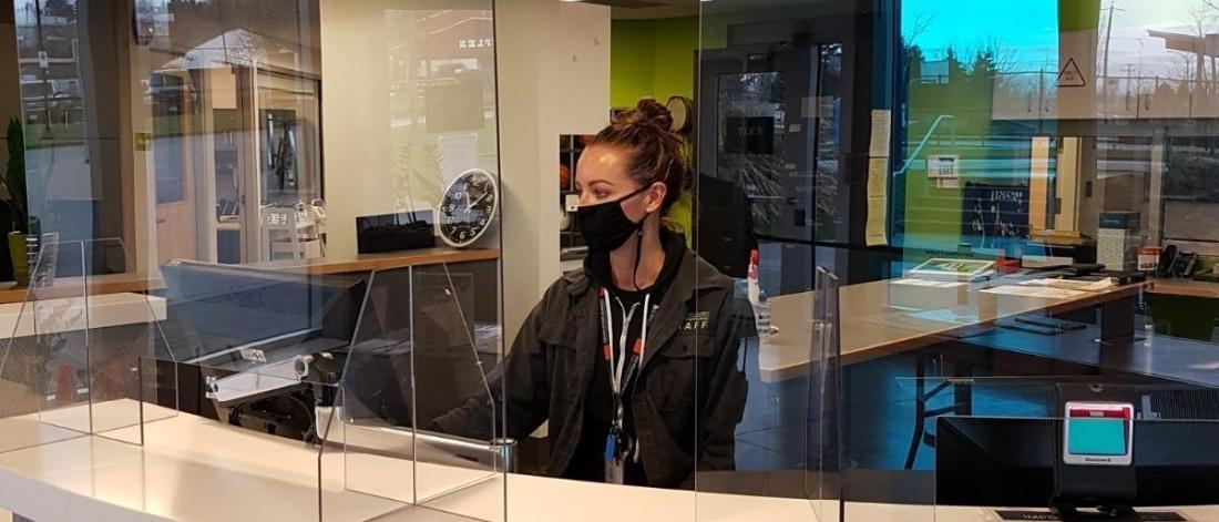 A woman in a black masks behind the lobby counter