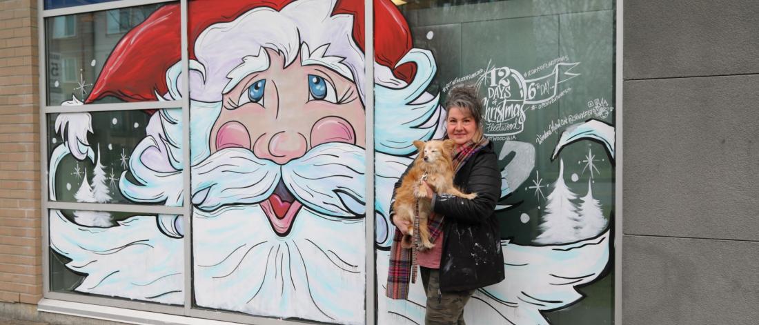 A woman standing by a painted mural of Santa Claus. Sparkle by Sylvia Designs.