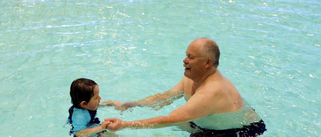 Grandpa and grandkid swimming. 