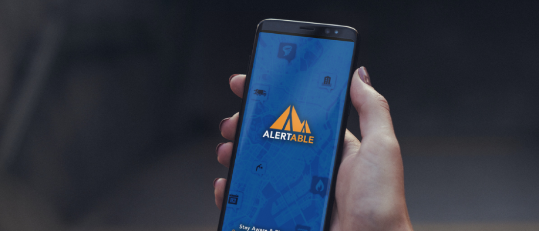 hand holding phone with alertable logo