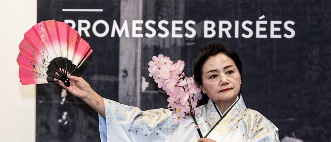 a woman in traditional Japanese attire dances with a fan