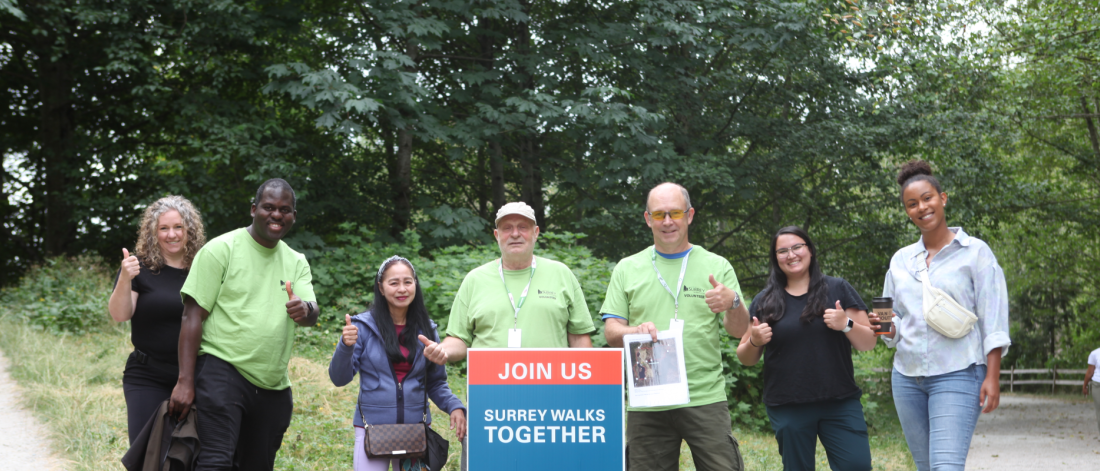 Several volunteers with a sign that says "Join Us - Surrey Walks Together"