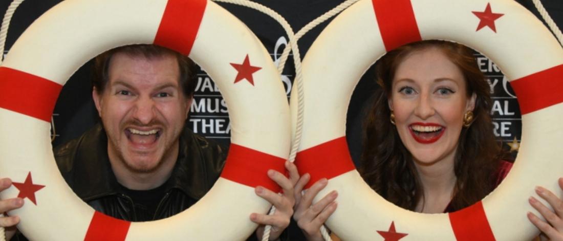 Two actors smile and hold up red and white life buoys