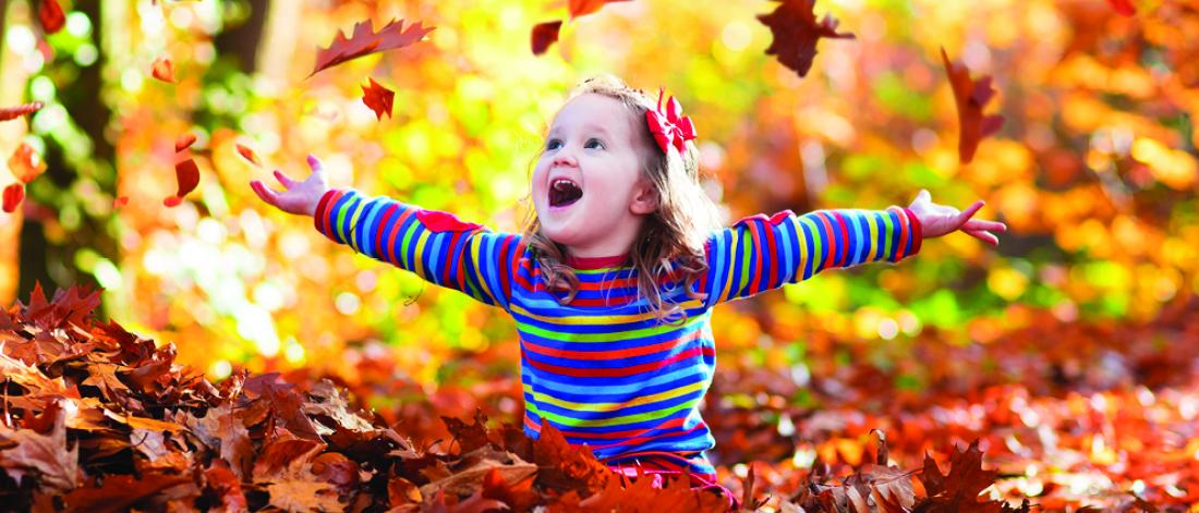 A girl playing with fall leaves. 