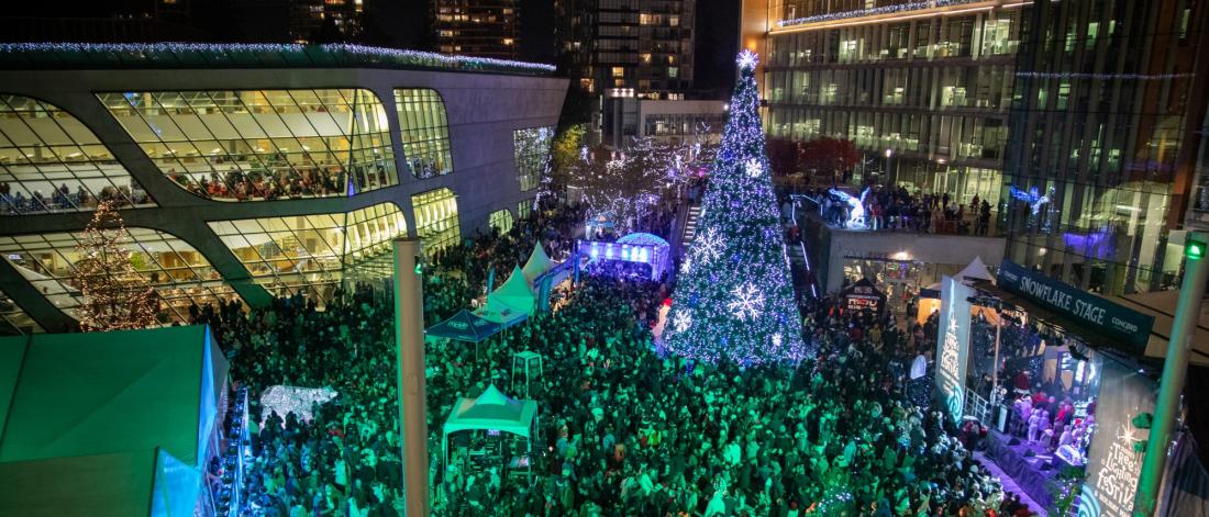 crowd gathers around large lit up christmas tree at surrey civic plaza