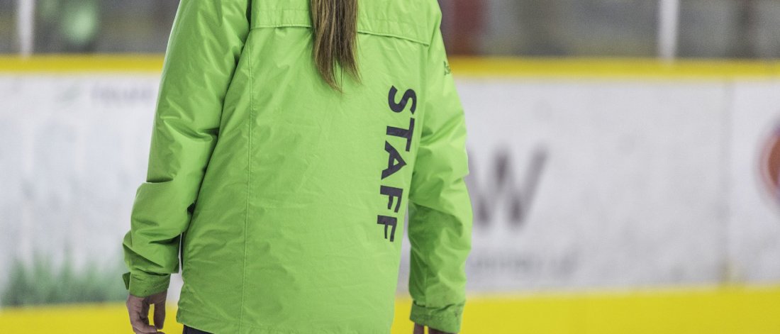 The back of an arenas staff wearing a green jacket.