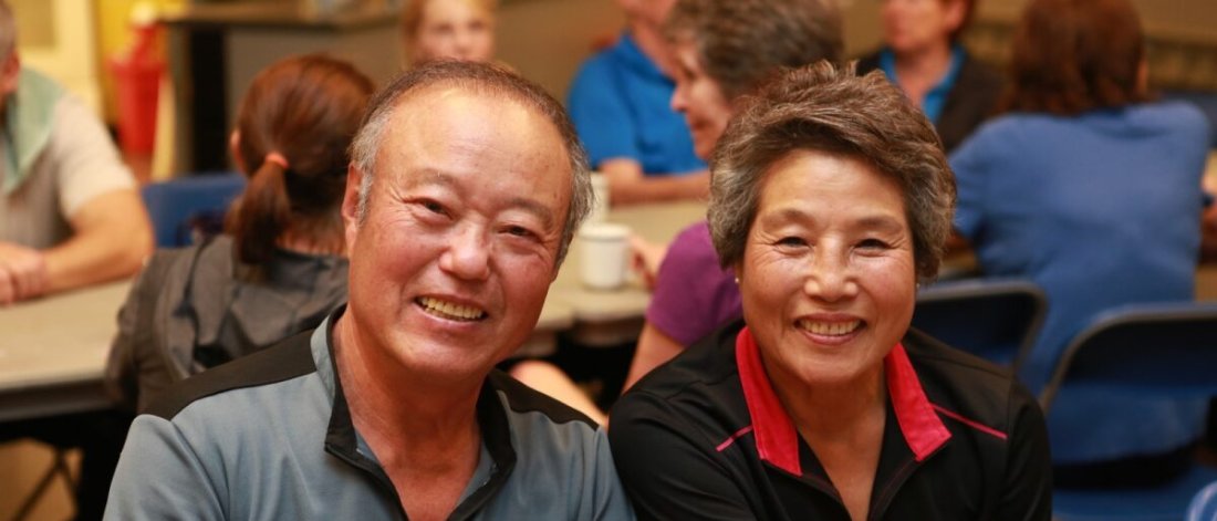 Two seniors smiling in a social setting.