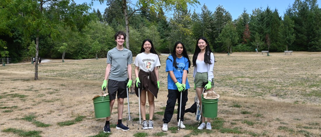 four people pose with park cleanup equipment