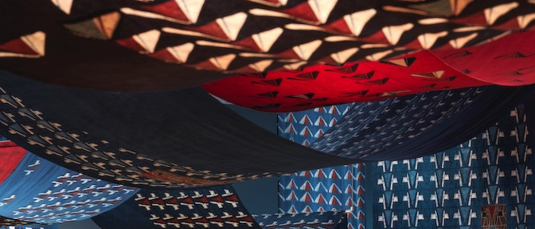 Red and blue cotton fabric with geometric patterns create a tent-like shape. 