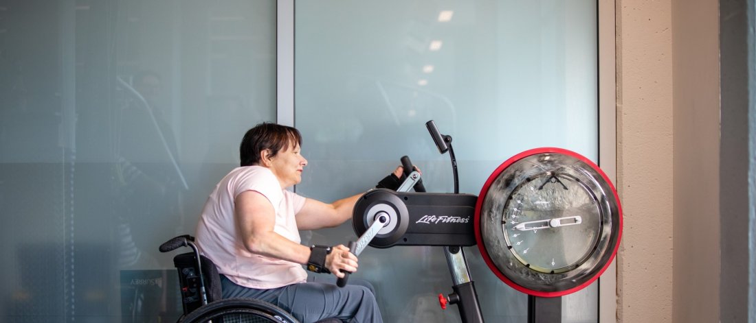 a woman in a wheelchair using a hand pedaling piece of exercise equipment
