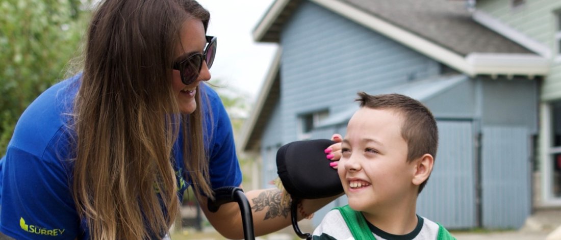  A woman leans in smiling at a joyous boy in a wheelchair.