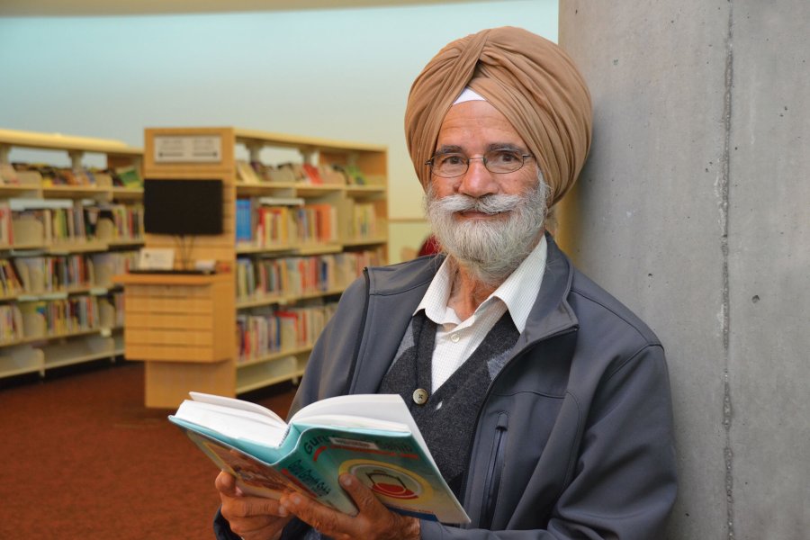 Senior man standing in a library holding a book
