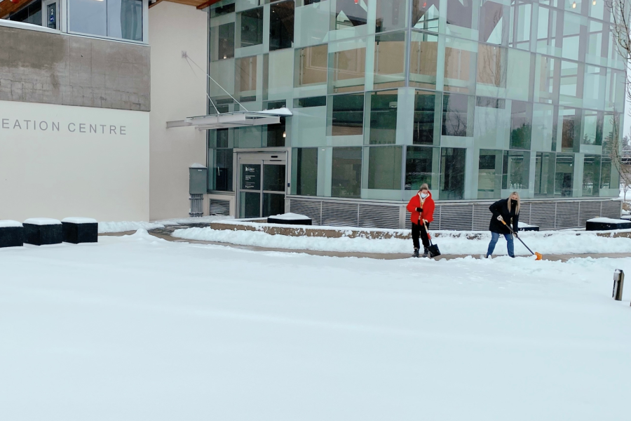two people shoveling snow in front of chuck bailey recreation centre