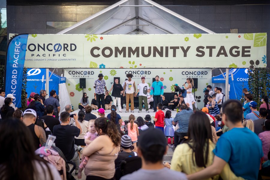 group of people in front of a stage with sign: community stage