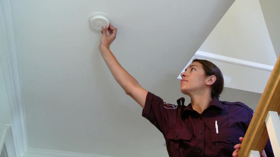 Firefighter checking smoke alarm in home