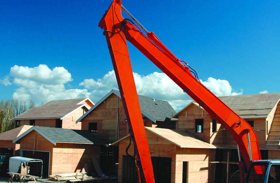 Red excavator in front of houses under construction