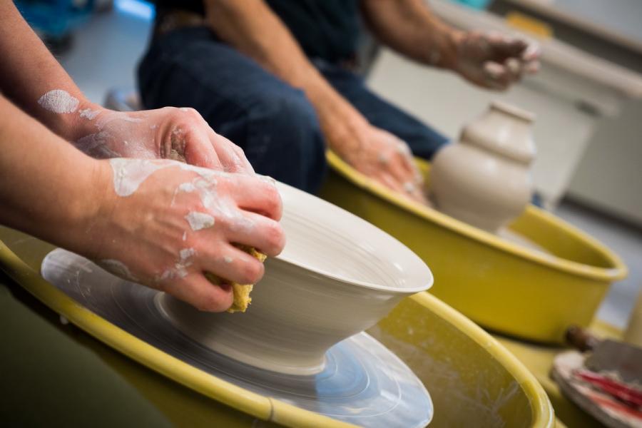 Close up of hands shaping clay bowls