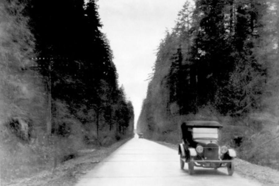 Two cars driving on the left side of the road, 1920