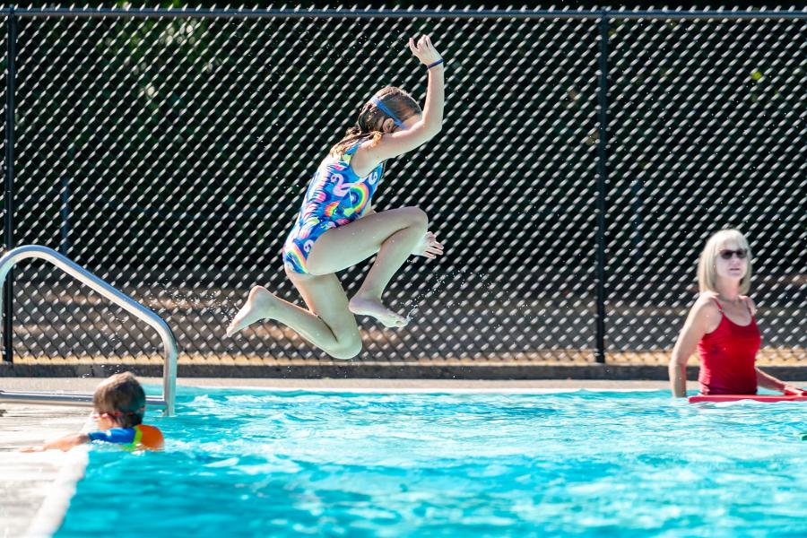 Girl jumping into outdoor pool