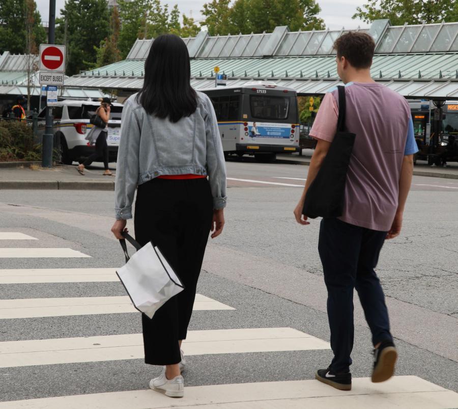 Two people in a crosswalk carrying cloth bags