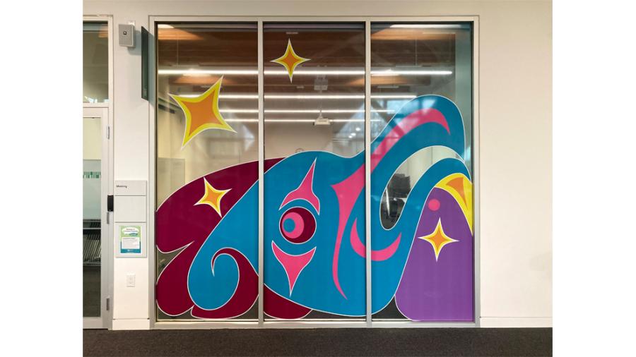 A colourful public artwork representing a coast salish thunderbird on windows of a meeting room