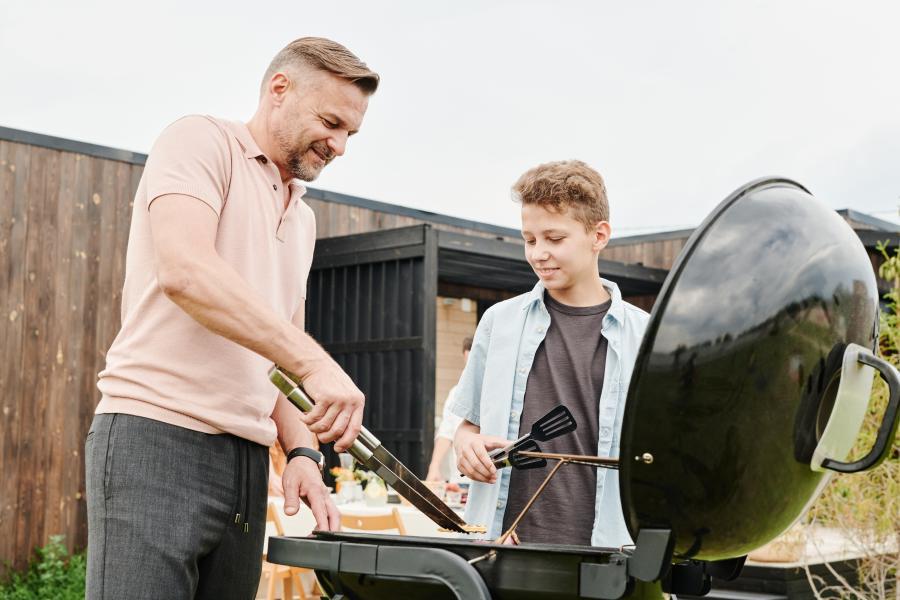 Father and son standing outside and grilling on a barbecue
