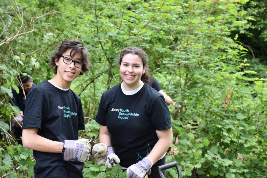 Two youth volunteers removing invasive plants.