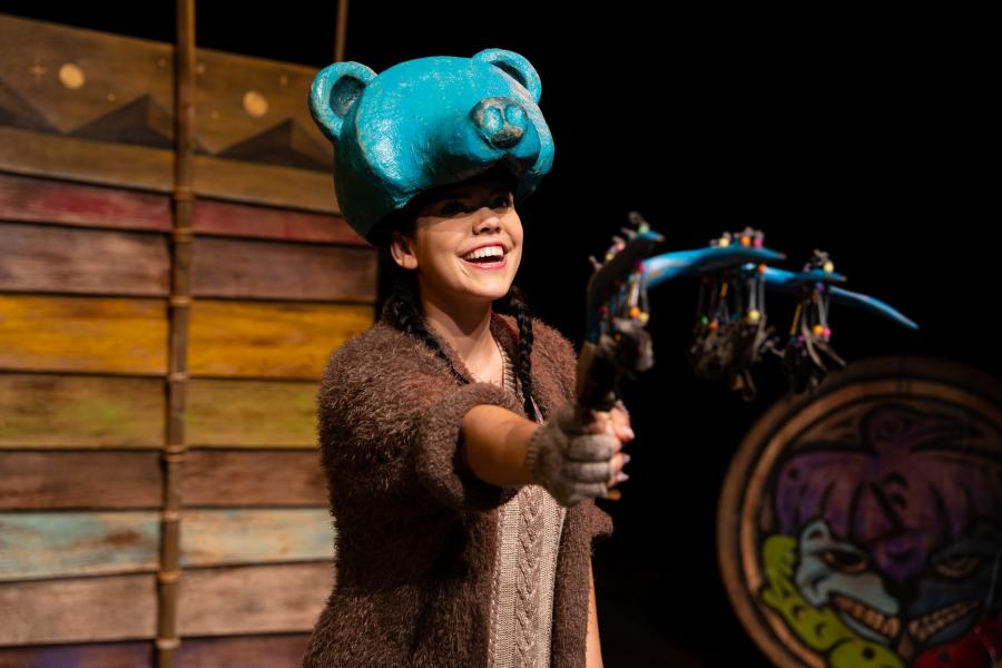 A woman in the performance of Th'owxiya wearing a blue traditional Coast Salish and Sto:lo bear mask on her head