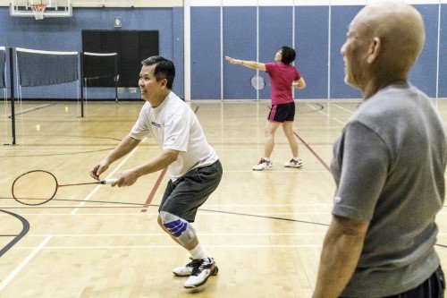 People playing badminton in a gymnasium.