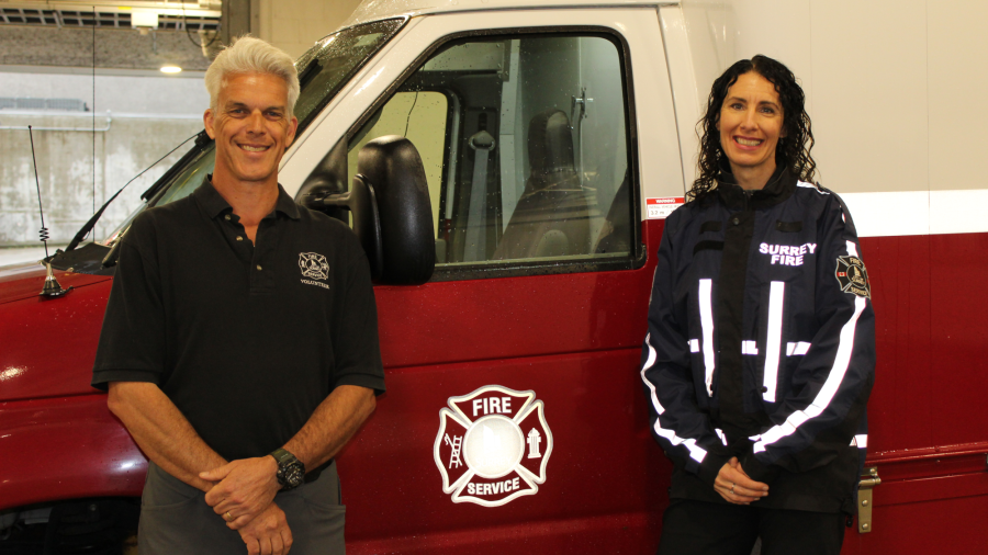 two volunteers pose by a fire service vehicle
