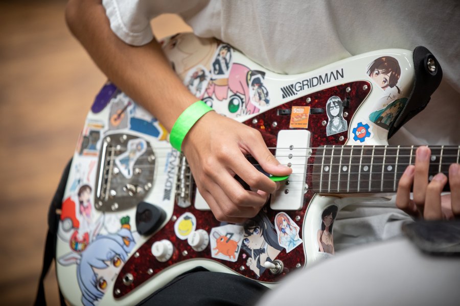 close up of person playing stickered electric guitar