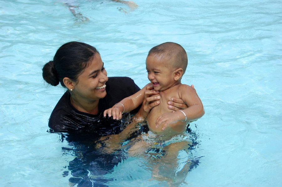 A mother swimming with their child.