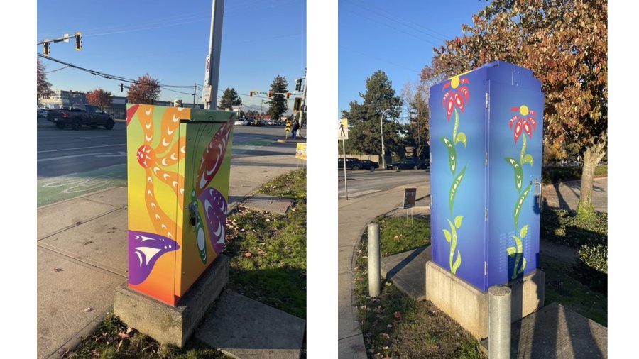 Vividly painted utility boxes featuring abstract floral designs stand on a sunny street corner with fall foliage in the background.