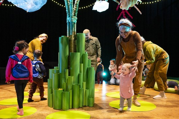 performers from tree interacting on set with audience of babies and children 