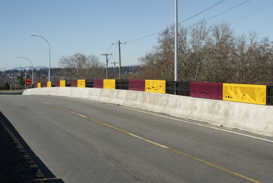 A side path with colorful barrier panels under a blue sky.
